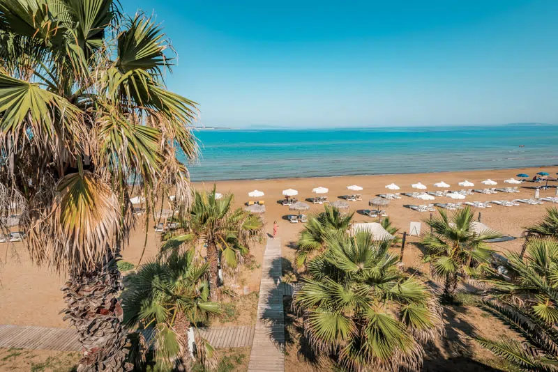 Rows of sunbeds and umbrellas on an organised sandy beach on Corfu's northeast coast